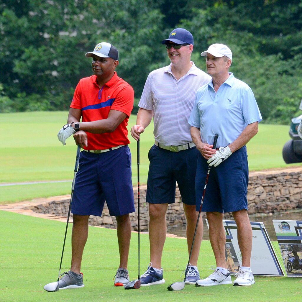 People holding golf clubs and smiling.